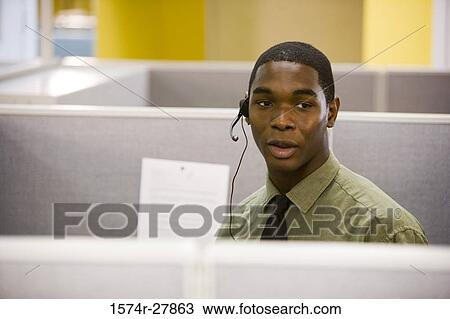 Stock Image - Young man using headset in an office. Fotosearch