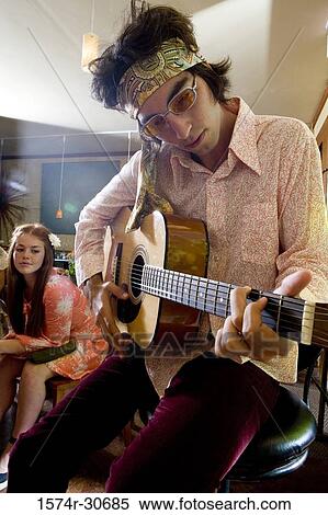 Young man with a guitar while sister sitting behind View Large Photo Image Stock Photography - Young man with a guitar while sister sitting behind. Fotosearch