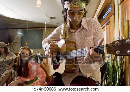Young man with a guitar while sisters sitting behind View Large Photo Image Stock Photograph - Young man with a guitar while sisters sitting behind. Fotosearch