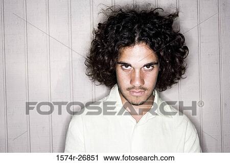 Stock Image - Young man with curly hair staring. Fotosearch