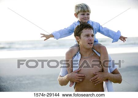 Young man with son on shoulders at the beach View Large Photo Image Picture - Young man with son on shoulders at the beach. Fotosearch