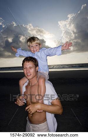 Young man with son on shoulders at the beach View Large Photo Image Stock Image - Young man with son on shoulders at the beach. Fotosearch