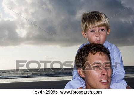 Young man with son on shoulders at the beach View Large Photo Image Stock Photography - Young man with son on shoulders at the beach. Fotosearch