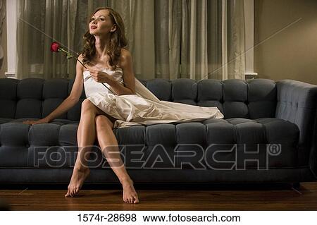 Stock Photo - Young prostitute holding a rose while sitting on a sofa. Fotosearch