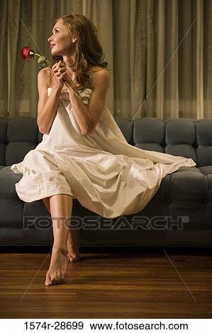 Stock Photo - Young prostitute holding a rose while sitting on a sofa. Fotosearch