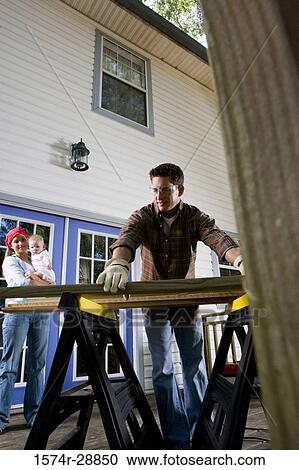 Young woman carrying baby while young man holding wood plank View Large Photo Image Stock Image - Young woman carrying baby while young man holding wood plank. Fotosearch