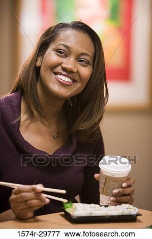 Young woman eating food and looking away View Large Photo Image Stock Photo - Young woman eating food and looking away. Fotosearch