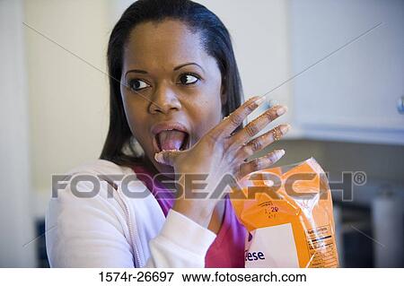 Young woman eating snacks in the kitchen View Large Photo Image Stock Photo - Young woman eating snacks in the kitchen. Fotosearch