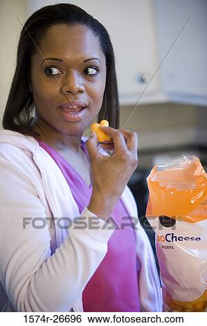 Young woman eating snacks in the kitchen View Large Photo Image Stock Photograph - Young woman eating snacks in the kitchen. Fotosearch
