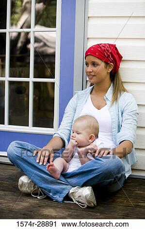Stock Image - Young woman holding baby on her lap. Fotosearch