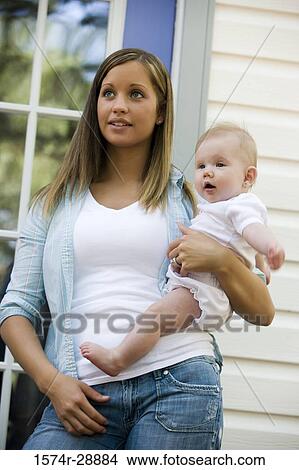 Young woman holding her baby and looking away View Large Photo Image Picture - Young woman holding her baby and looking away. Fotosearch