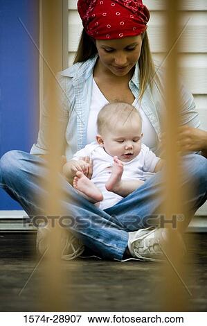 Stock Photo - Young woman holding her baby on lap. Fotosearch