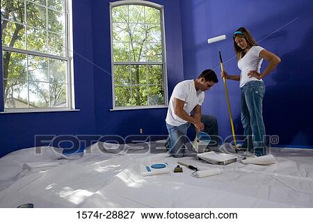 Young woman holding paint roller while young man poring paint in paint tray View Large Photo Image Stock Photo - Young woman holding paint roller while young man poring paint in paint tray. Fotosearch