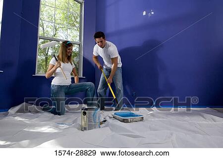 Young woman holding paint roller while young man preparing color View Large Photo Image Stock Photo - Young woman holding paint roller while young man preparing color. Fotosearch