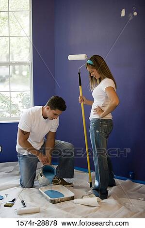 Young woman holding paint roller while young man pouring paint in paint tray View Large Photo Image Stock Photo - Young woman holding paint roller while young man pouring paint in paint tray. Fotosearch