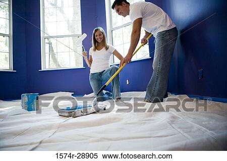 Young woman holding paint roller while young man preparing color View Large Photo Image Stock Photography - Young woman holding paint roller while young man preparing color. Fotosearch