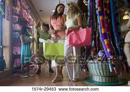 Young woman holding shopping bags with children in background View Large Photo Image Stock Image - Young woman holding shopping bags with children in background. Fotosearch