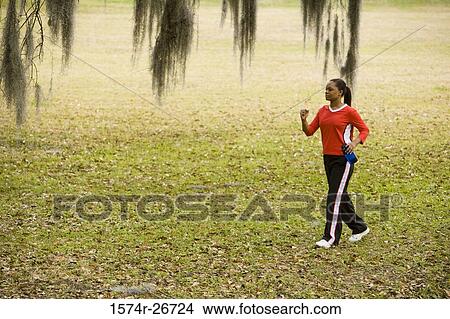 Young woman in sports clothing jogging on ground View Large Photo Image Picture - Young woman in sports clothing jogging on ground. Fotosearch