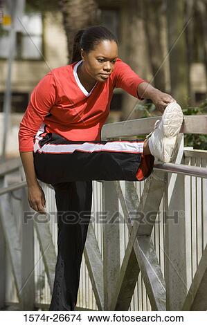 Young woman in sports clothing exercising by a fence View Large Photo Image Picture - Young woman in sports clothing exercising by a fence. Fotosearch