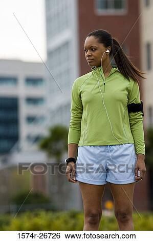 Young woman in sports clothing standing with building in the background View Large Photo Image Stock Photograph - Young woman in sports clothing standing with building in the background. Fotosearch