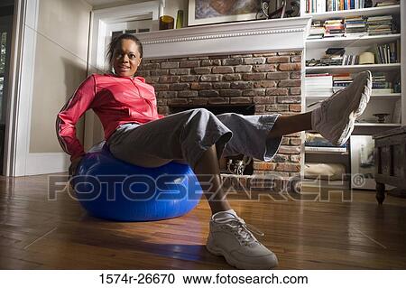 Young woman in sports clothing exercising on fitness ball by fire place View Large Photo Image Stock Image - Young woman in sports clothing exercising on fitness ball by fire place. Fotosearch