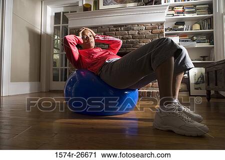 Young woman in sports clothing exercising on fitness ball by fire place View Large Photo Image Stock Image - Young woman in sports clothing exercising on fitness ball by fire place. Fotosearch