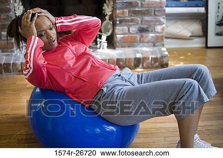 Young woman in sports clothing exercising on fitness ball by fire place View Large Photo Image Stock Image - Young woman in sports clothing exercising on fitness ball by fire place. Fotosearch