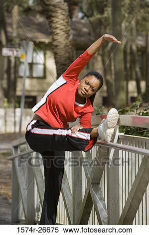 Young woman in sports clothing exercising by a fence View Large Photo Image Stock Photography - Young woman in sports clothing exercising by a fence. Fotosearch