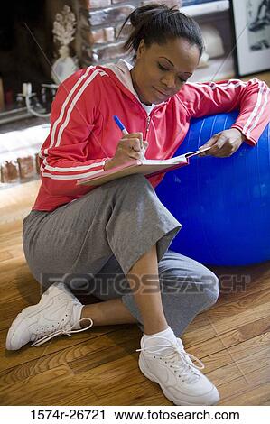 Young woman in sports clothing writing in a book by fitness ball View Large Photo Image Stock Image - Young woman in sports clothing writing in a book by fitness ball. Fotosearch