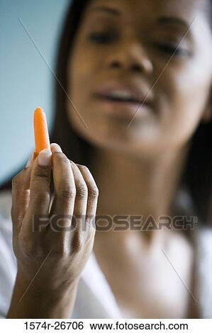 Young woman looking at a piece of carrot View Large Photo Image Stock Photograph - Young woman looking at a piece of carrot. Fotosearch