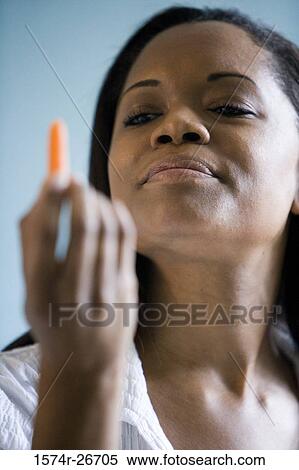 Young woman looking at a piece of carrot View Large Photo Image Stock Photography - Young woman looking at a piece of carrot. Fotosearch