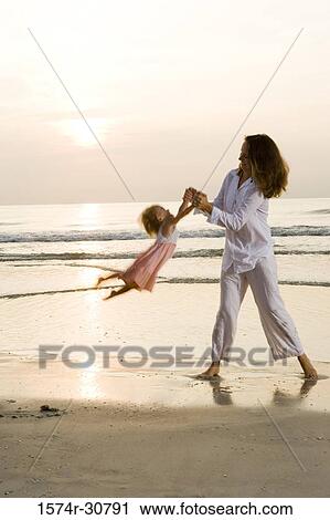 Stock Image - Young woman playing with daughter on the beach. Fotosearch
