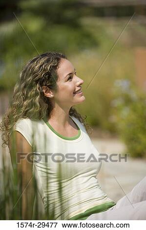 Young woman sitting and smiling View Large Photo Image Stock Photo - Young woman sitting and smiling. Fotosearch