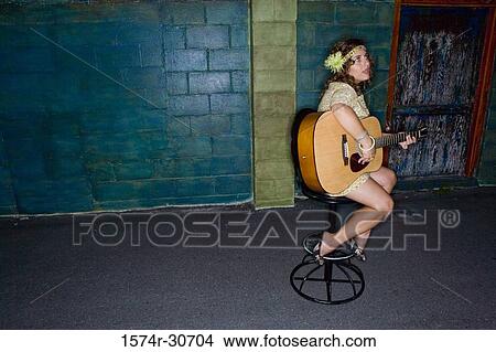 Young woman sitting with a guitar and looking up View Large Photo Image Picture - Young woman sitting with a guitar and looking up. Fotosearch