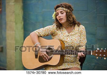 Young woman sitting with a guitar View Large Photo Image Stock Image - Young woman sitting with a guitar. Fotosearch