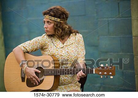Young woman sitting with a guitar View Large Photo Image Stock Photo - Young woman sitting with a guitar. Fotosearch