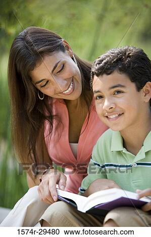 Young woman sitting with her son reading book View Large Photo Image Stock Image - Young woman sitting with her son reading book. Fotosearch