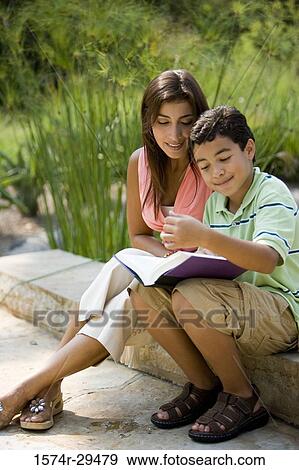 Young woman sitting with her son reading book View Large Photo Image Stock Photo - Young woman sitting with her son reading book. Fotosearch