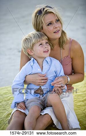 Young woman sitting with son at the beach View Large Photo Image Stock Image - Young woman sitting with son at the beach. Fotosearch