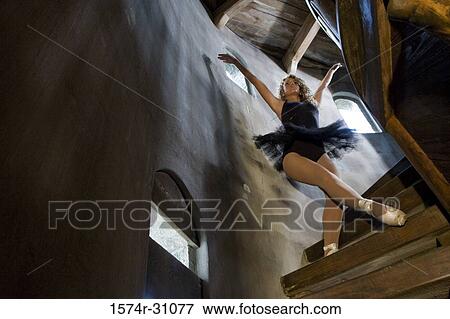 Stock Photo - Young woman wearing a tutu and dancing on wooden staircase. Fotosearch