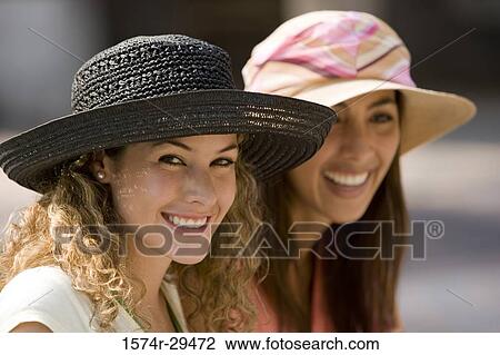 Stock Image - Young women sitting together and smiling. Fotosearch