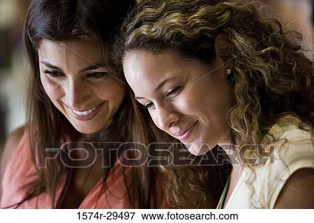 Young women standing together in store View Large Photo Image Stock Photo - Young women standing together in store. Fotosearch