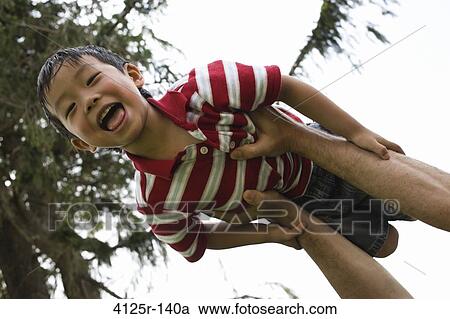 Asian boy laughing with mouth open being thrown in air by Father, USA View Large Photo Image Stock Image - Asian boy laughing with mouth open being thrown in air by Father, USA. Fotosearch