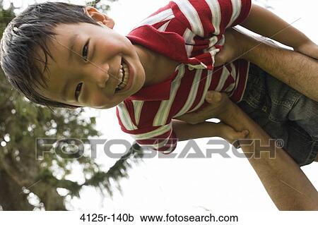Asian boy smiling while father holds him above his head, USA View Large Photo Image Stock Image - Asian boy smiling while father holds him above his head, USA. Fotosearch