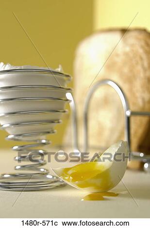 Stock Image - Boiled egg and toast with yolk dripping from egg shell. Fotosearch