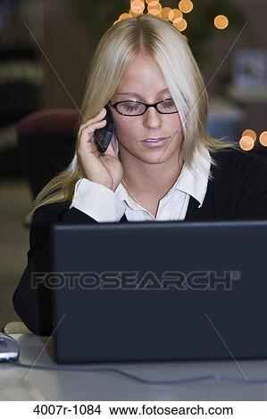 Picture - Businesswoman talking on a mobile phone and using a laptop, Florida, USA. Fotosearch