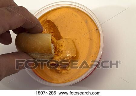 Stock Photograph - Close-up of a person's hand dipping into dip. Fotosearch
