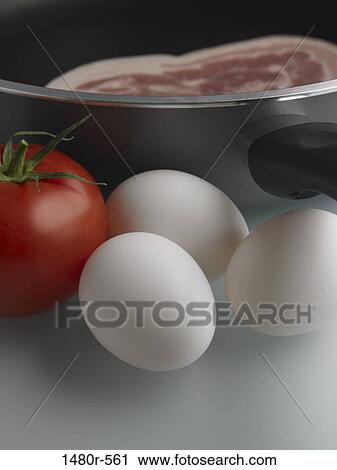 Close-up of a tomato with eggs and bacon in the pan View Large Photo Image Stock Image - Close-up of a tomato with eggs and bacon in the pan. Fotosearch
