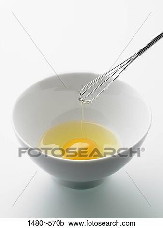 Stock Image - Close-up of a wire whisk and egg yolk in a bowl. Fotosearch