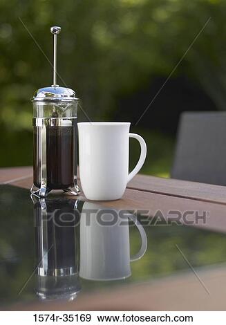 Coffee cup and a plunger on a table View Large Photo Image Stock Photo - Coffee cup and a plunger on a table. Fotosearch